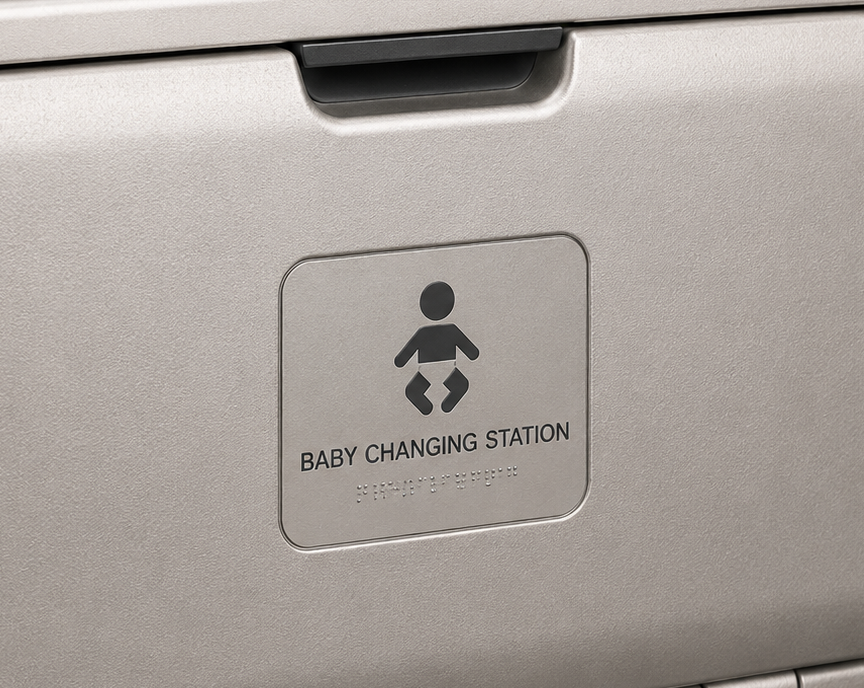 Metallic baby changing station panel with icon and text on a dark background